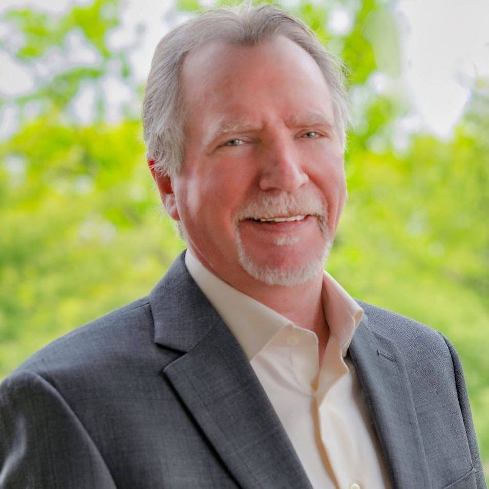 Professional headshot of Steve Capachietti with lake background